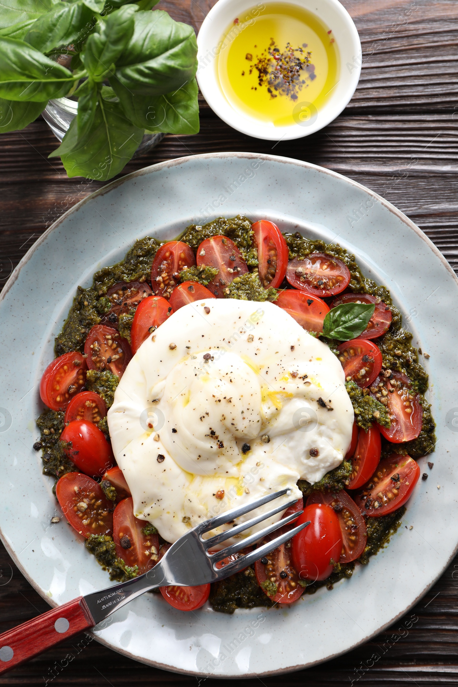 Photo of Fresh delicious burrata salad served on wooden table, top view