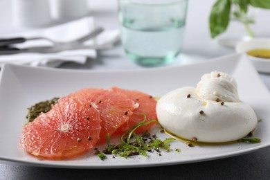 Photo of Delicious burrata cheese, grapefruit and spices on table, closeup