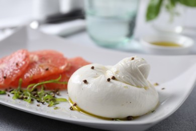 Delicious burrata cheese, grapefruit and spices on table, closeup