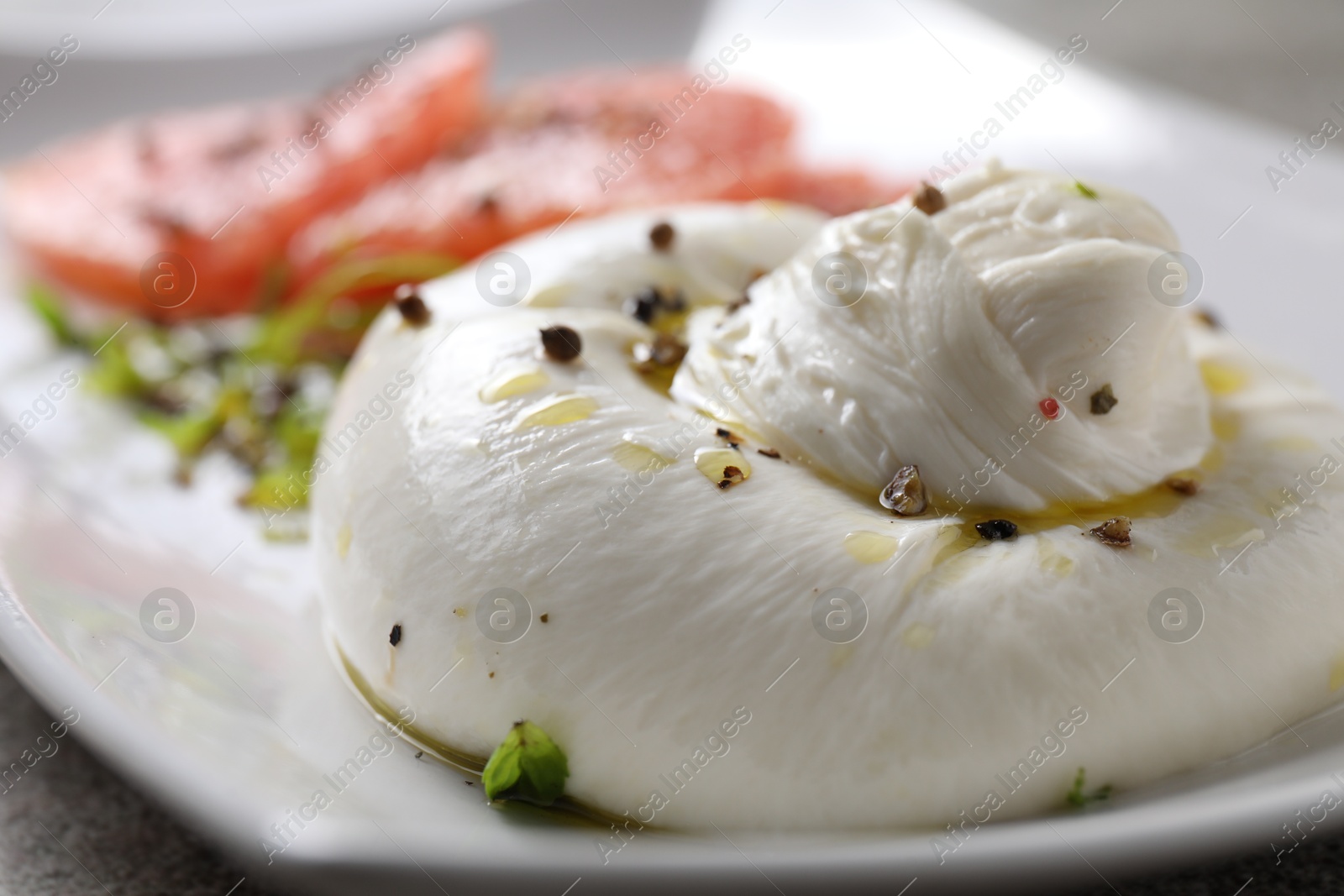 Photo of Delicious burrata cheese and spices on table, closeup