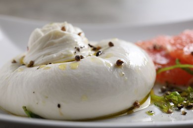 Photo of Delicious burrata cheese and spices on plate, closeup