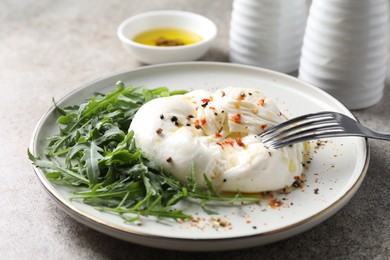 Photo of Delicious burrata cheese, arugula and spices on grey table, closeup