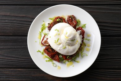 Photo of Delicious burrata cheese and sun-dried tomatoes on wooden table, top view