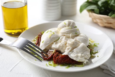 Delicious burrata cheese and sun-dried tomatoes served on white table, closeup