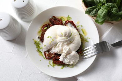 Photo of Delicious burrata cheese and sun-dried tomatoes served on white table, top view