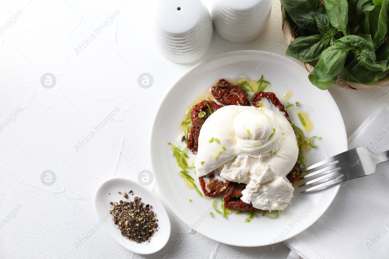 Photo of Delicious burrata cheese and sun-dried tomatoes served on white table, top view. Space for text