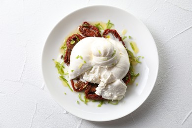 Delicious burrata cheese and sun-dried tomatoes on white table, top view