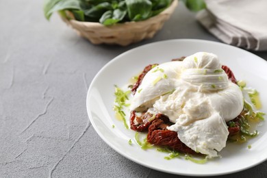 Photo of Delicious burrata cheese and sun-dried tomatoes on light grey table, closeup. Space for text