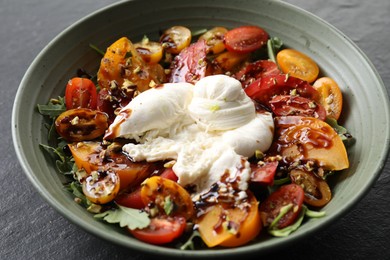 Fresh delicious burrata salad on black table, closeup