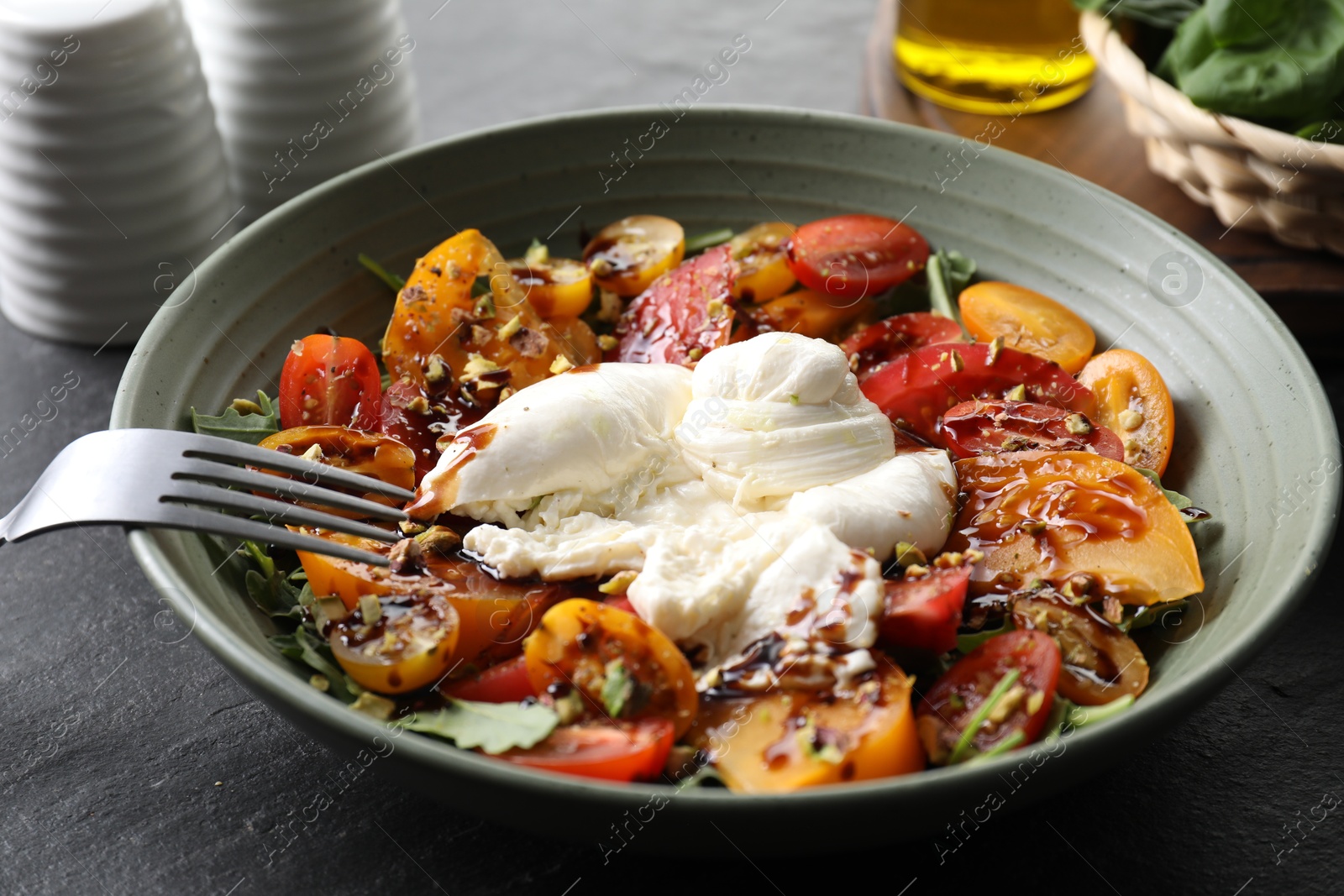 Photo of Fresh delicious burrata salad served on black table, closeup