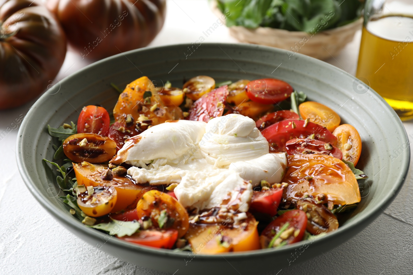 Photo of Fresh delicious burrata salad served on white table, closeup