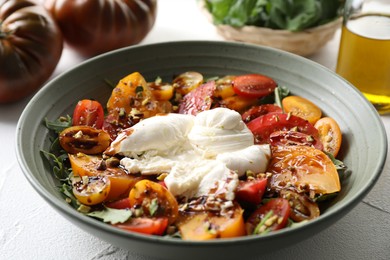 Photo of Fresh delicious burrata salad served on white table, closeup