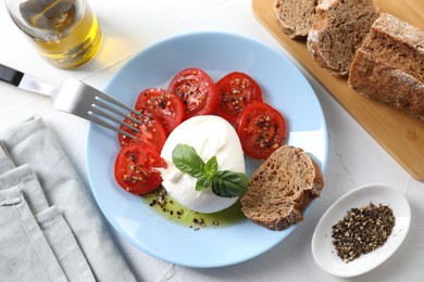 Delicious burrata cheese, tomatoes, basil, bread and spices on white table, top view