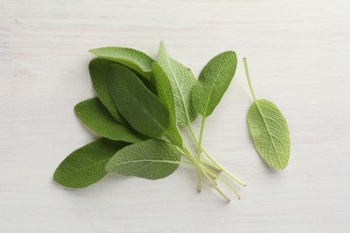 Photo of Fresh sage leaves on light wooden table, top view