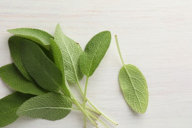 Photo of Fresh sage leaves on light wooden table, top view