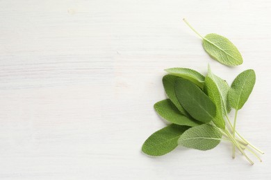 Photo of Fresh sage leaves on light wooden table, top view. Space for text