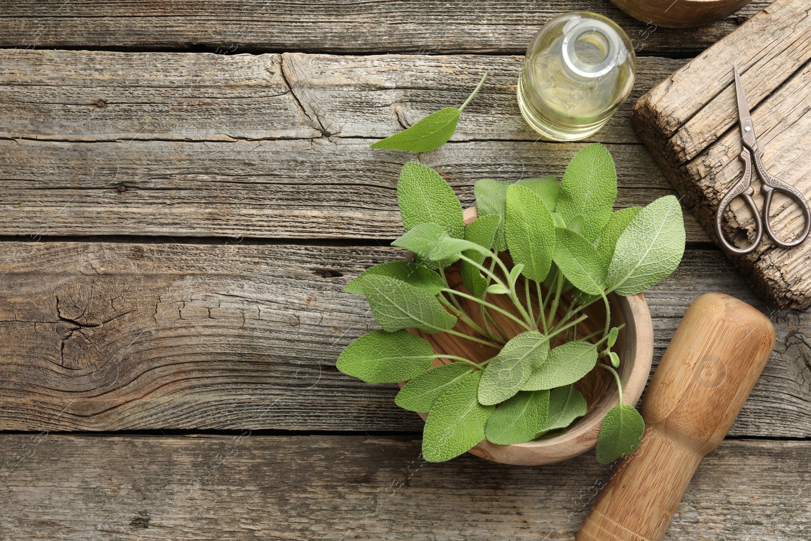 Photo of Fresh sage leaves, mortar, pestle, bottle of oil and scissors on wooden table, flat lay. Space for text