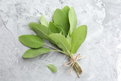 Photo of Bunch of fresh sage leaves on gray textured table, top view