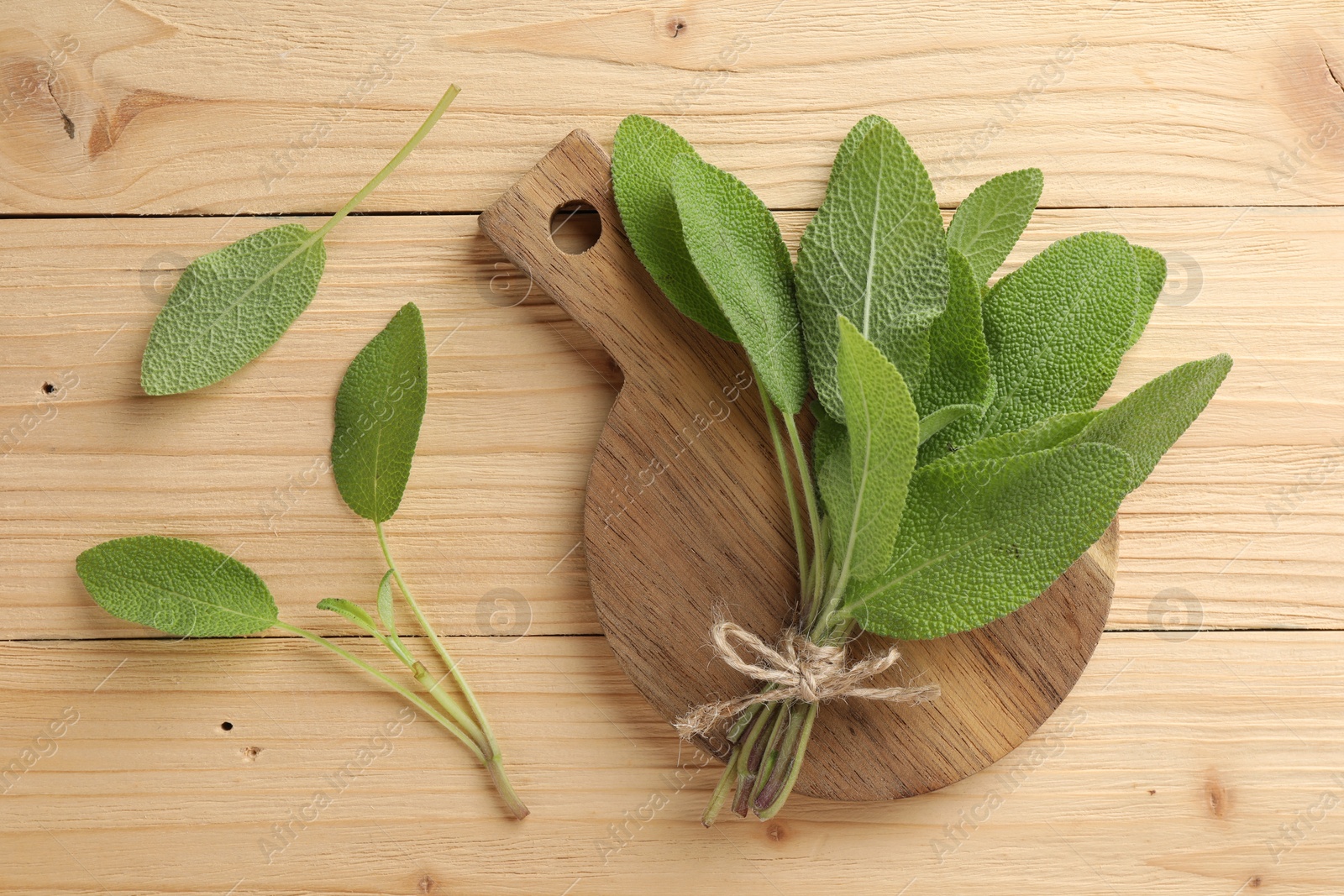 Photo of Bunch of fresh sage leaves on wooden table, flat lay