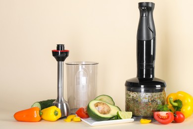 Photo of Hand blender kit and fresh products on beige background