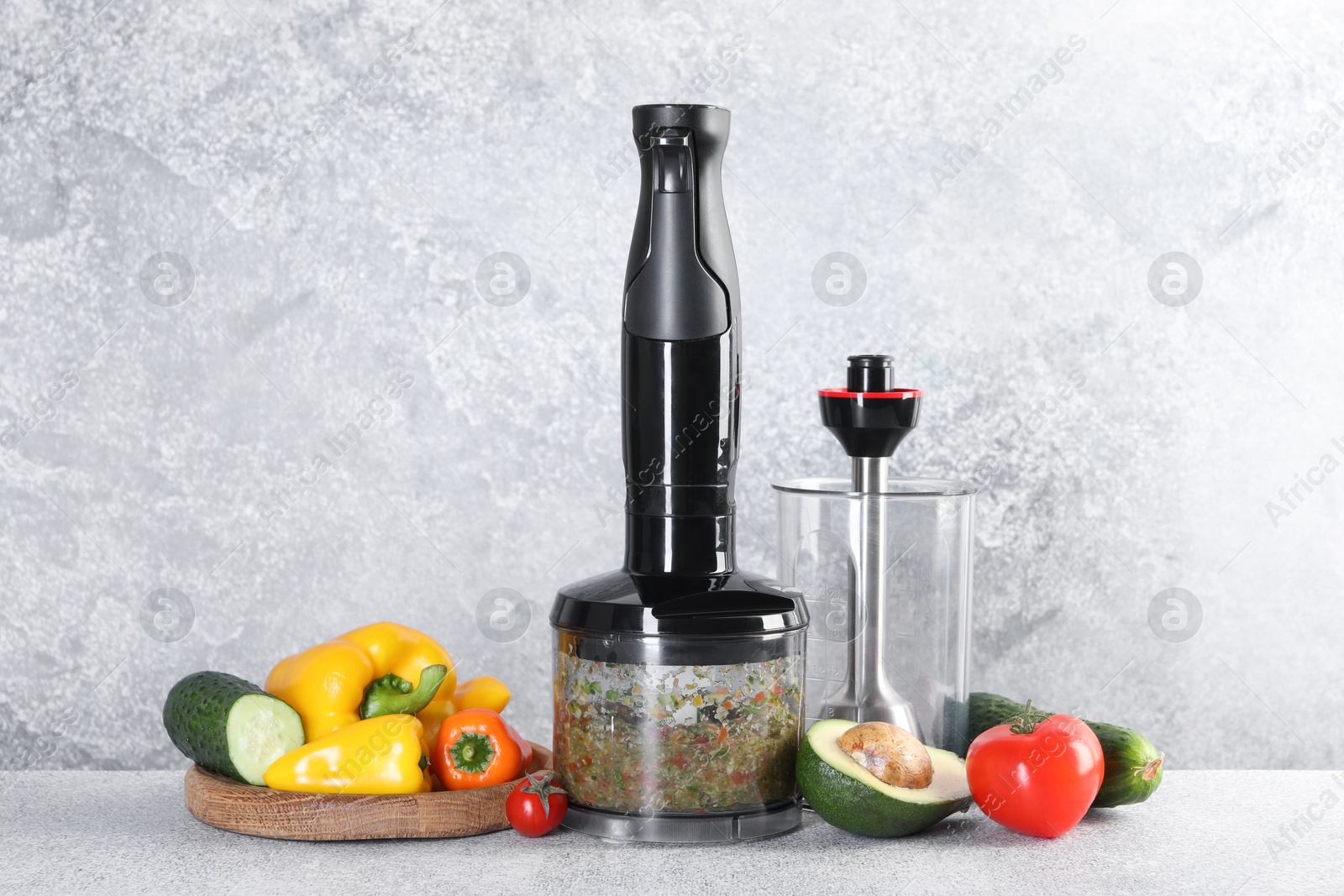 Photo of Hand blender kit, mixture of ingredients and fresh products on light grey table