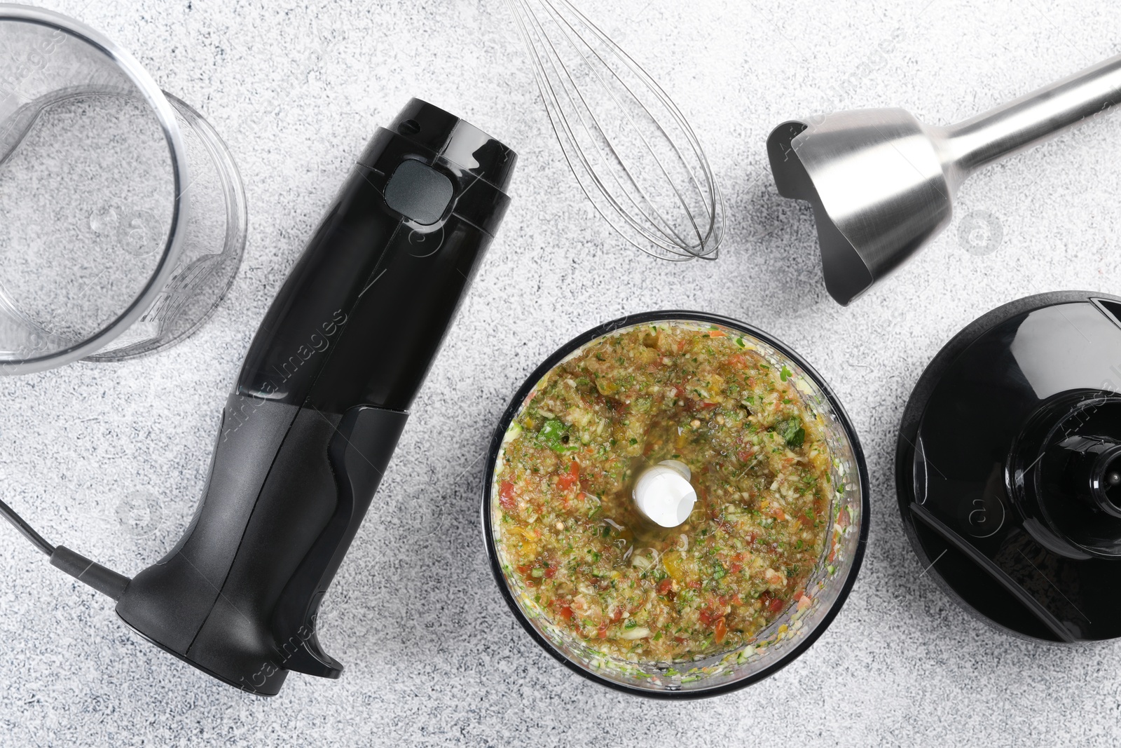 Photo of Hand blender kit and mixture of ingredients on light grey table, flat lay