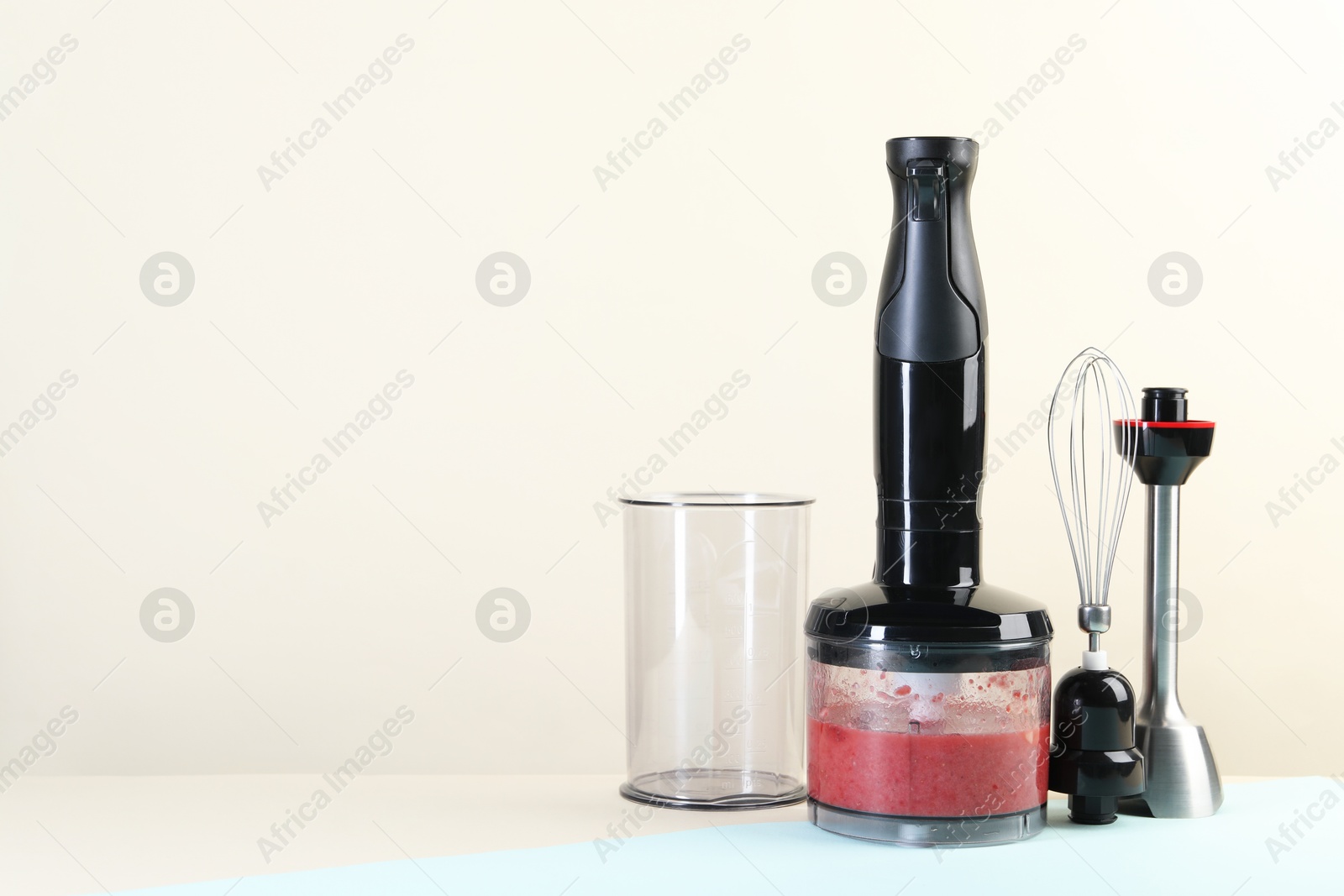 Photo of Hand blender kit and mixture of ingredients on color background, space for text