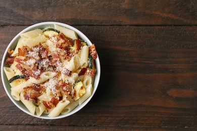 Photo of Tasty pasta with bacon and cheese on wooden table, top view. Space for text