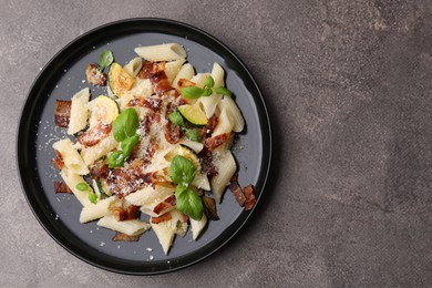 Photo of Tasty pasta with bacon and basil on brown table, top view. Space for text