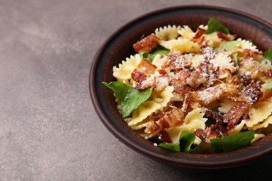 Photo of Tasty pasta with bacon and basil on brown table, space for text