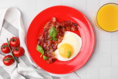 Fried egg and bacon served on white tiled table, top view