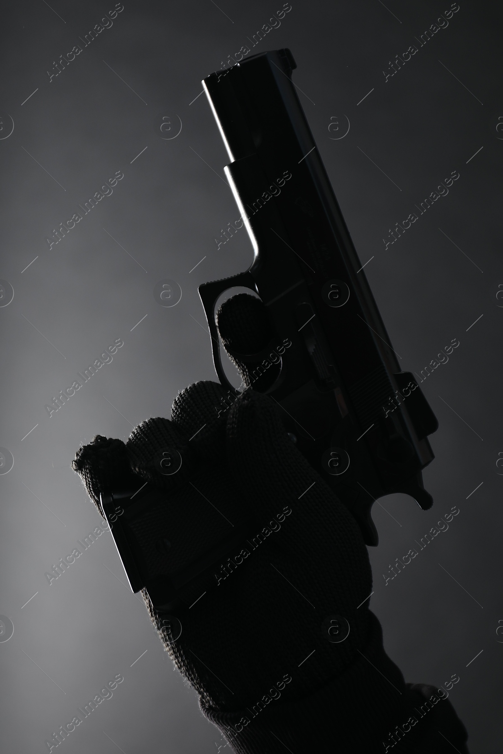 Photo of Dangerous criminal with gun on black background, closeup. Armed robbery