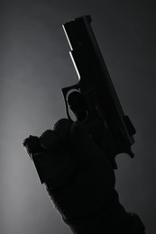 Dangerous criminal with gun on black background, closeup. Armed robbery