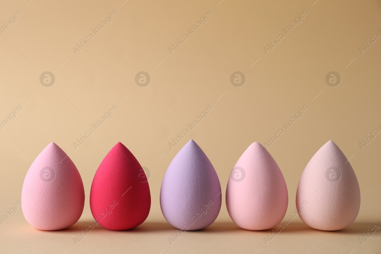 Photo of Many colorful makeup sponges on beige background