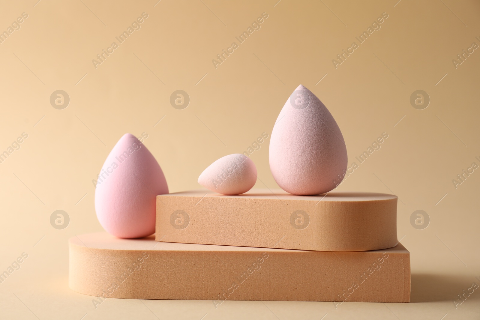 Photo of Stylish presentation of makeup sponges on beige background