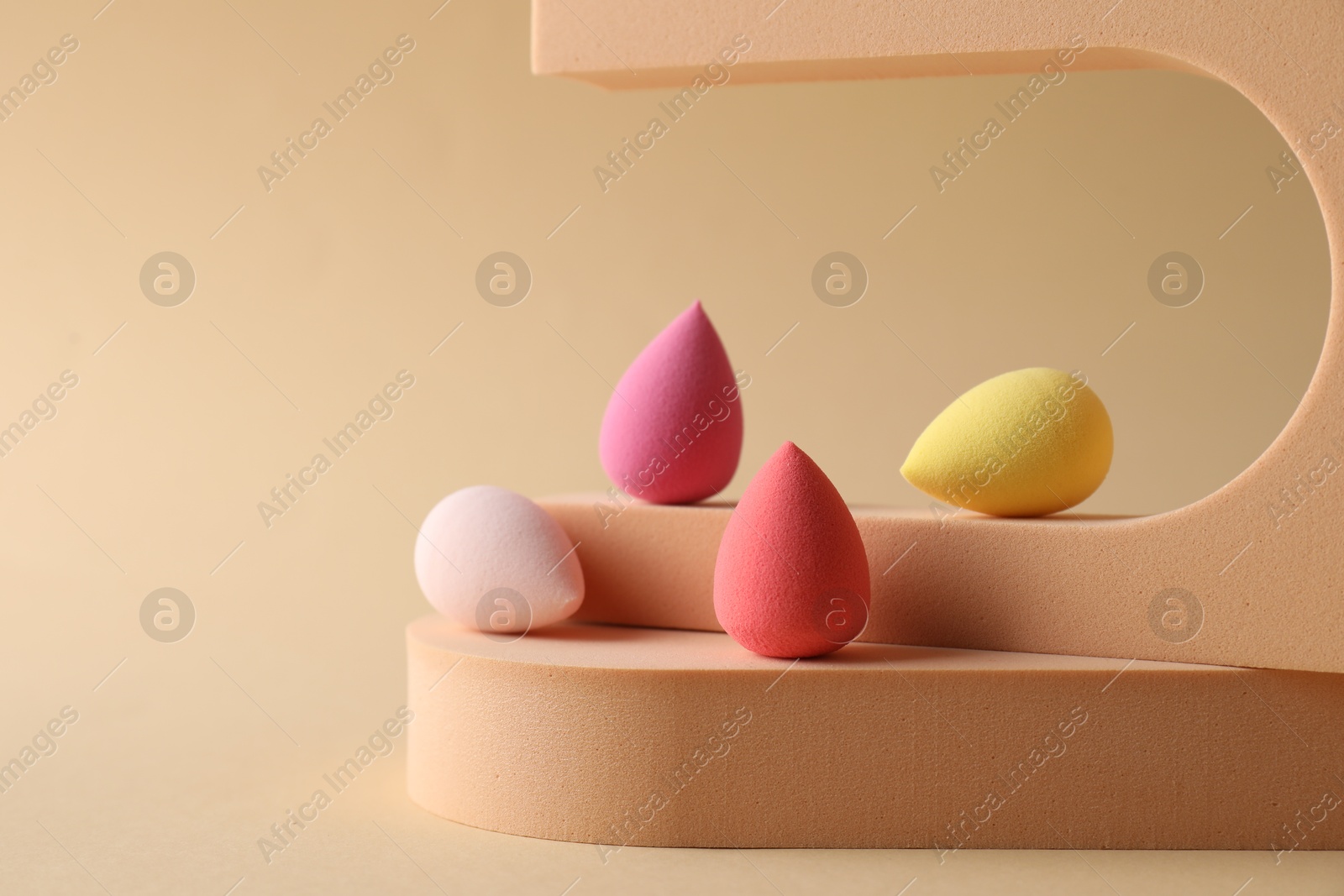 Photo of Stylish presentation of makeup sponges on beige background, space for text