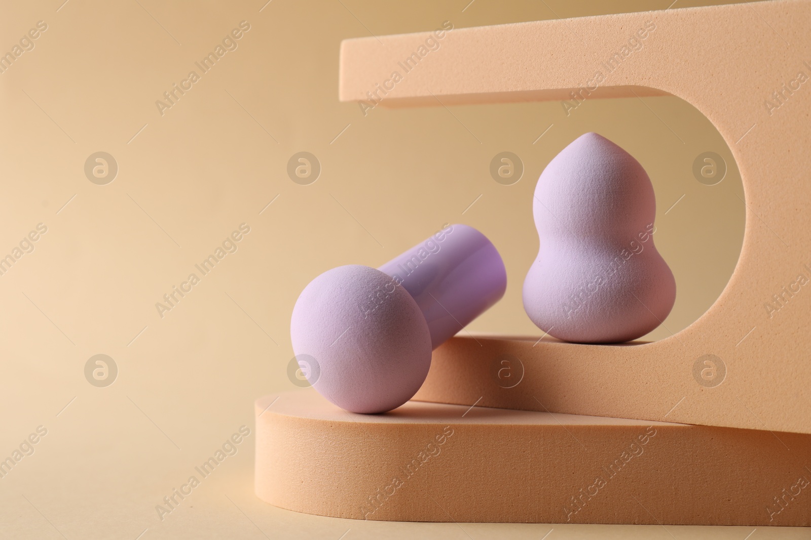 Photo of Stylish presentation of makeup sponges on beige background, space for text