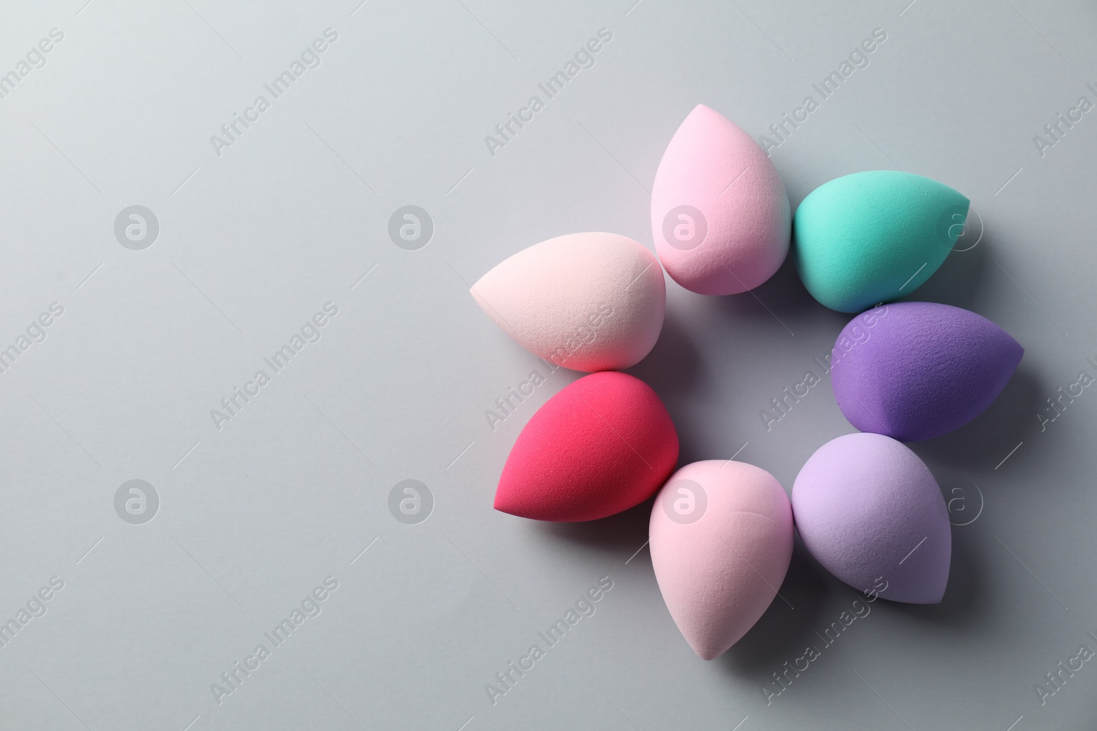 Photo of Many colorful makeup sponges on grey background, flat lay. Space for text