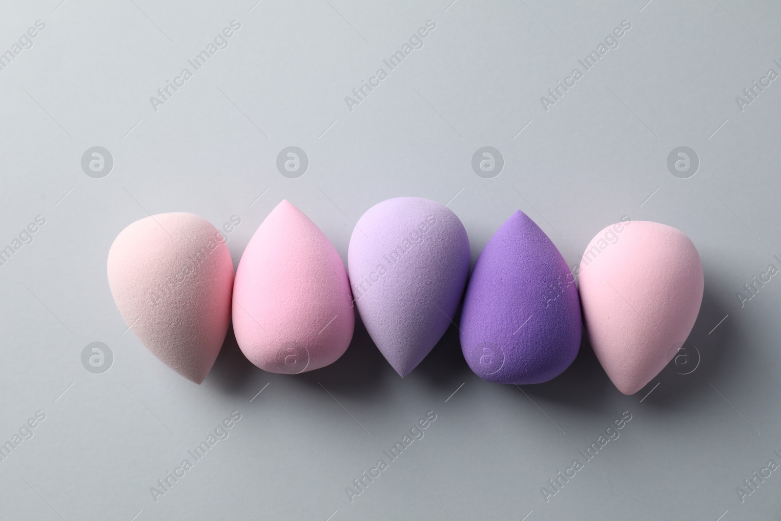 Photo of Many colorful makeup sponges on grey background, flat lay