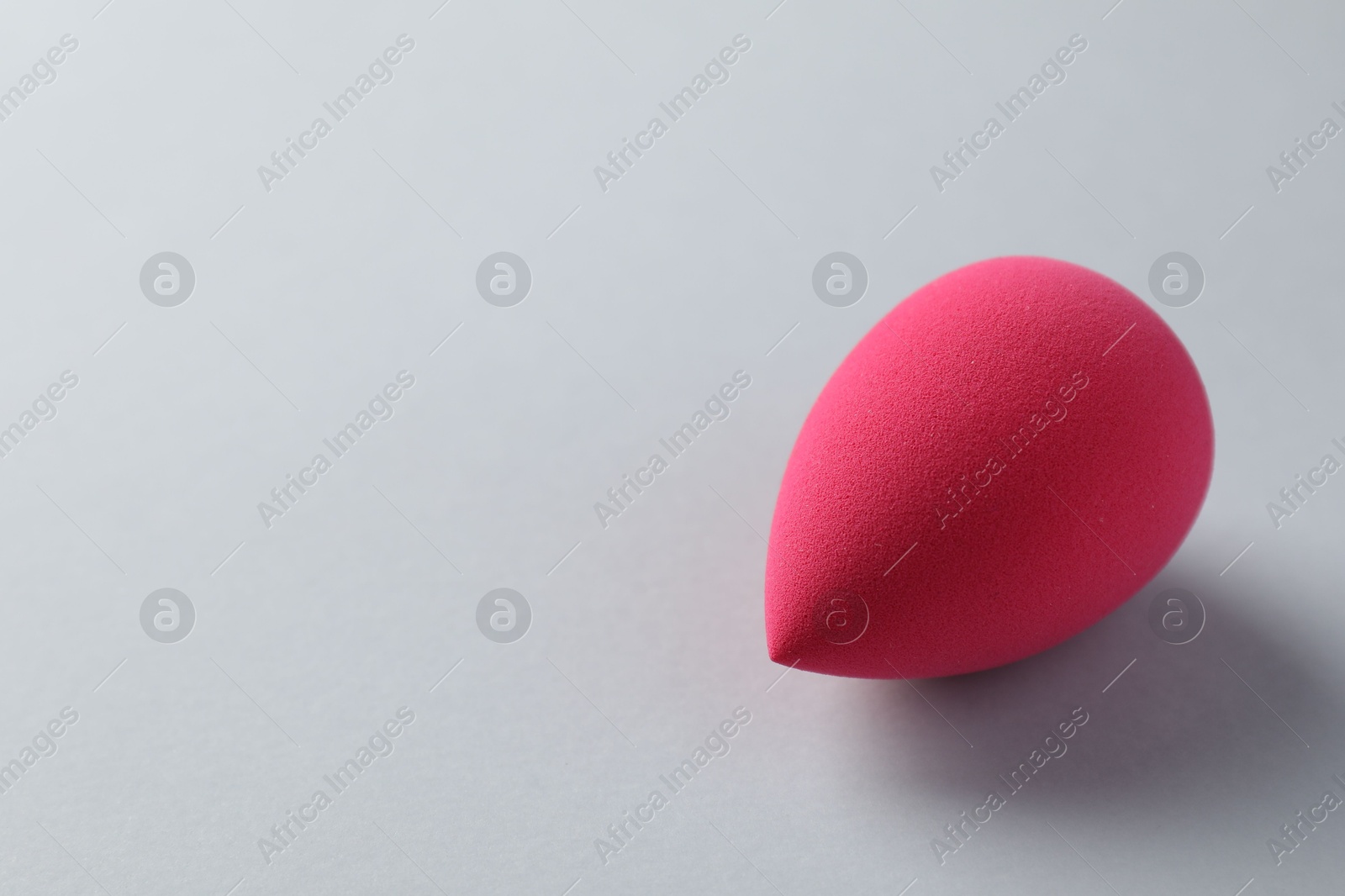 Photo of One pink makeup sponge on grey background, space for text