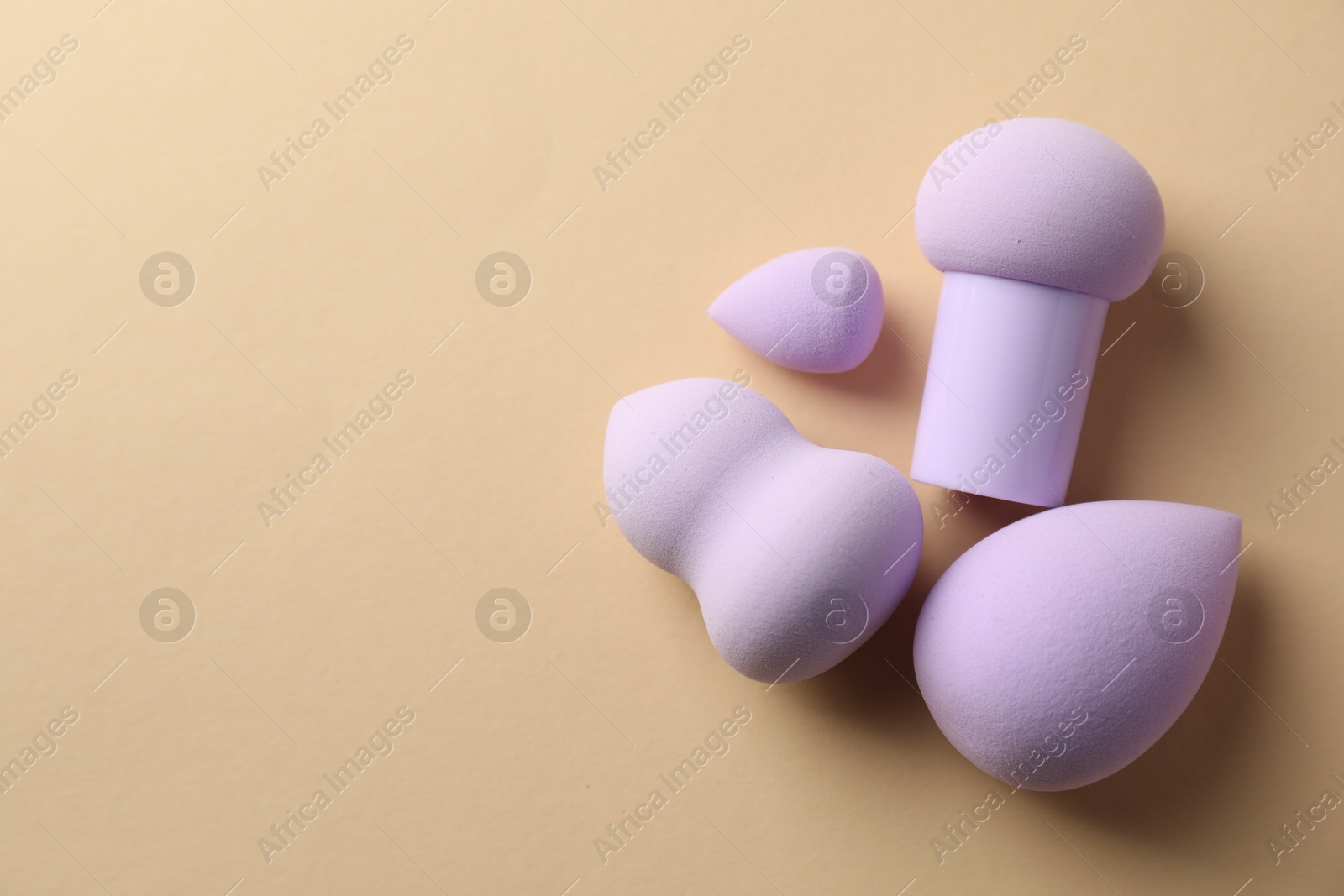 Photo of Many violet makeup sponges on beige background. flat lay. Space for text