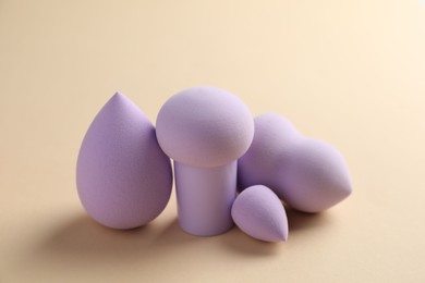 Photo of Many violet makeup sponges on beige background