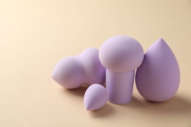 Photo of Many violet makeup sponges on beige background