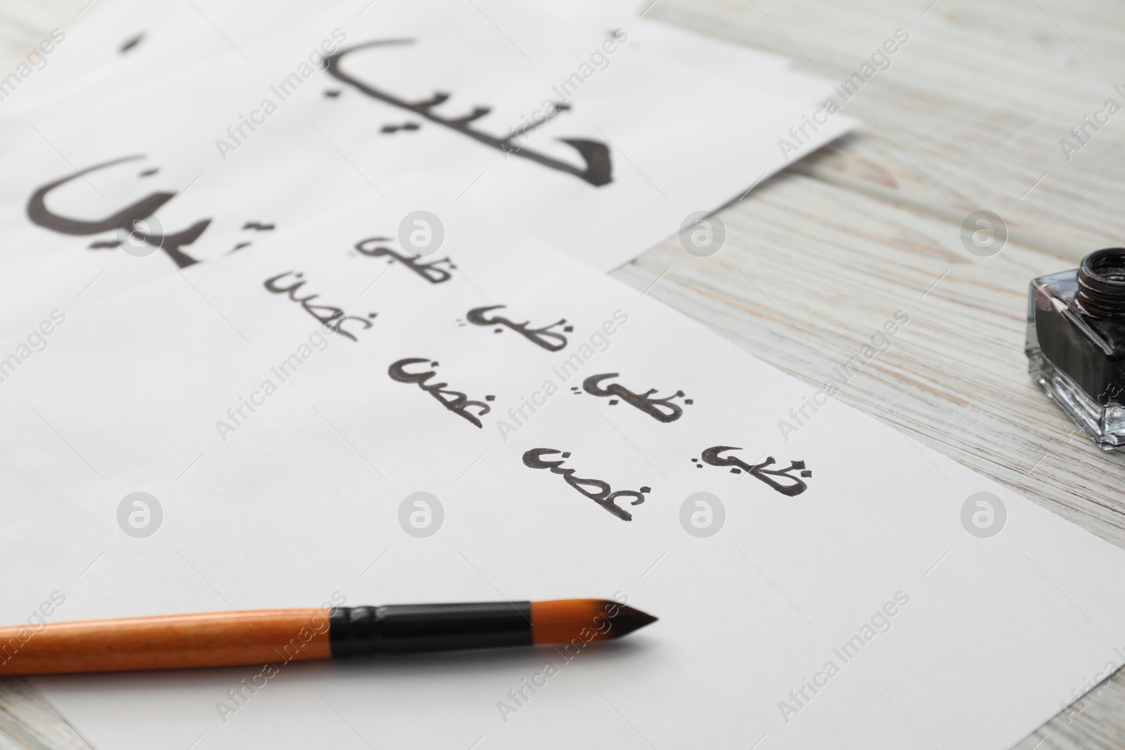 Photo of Calligraphy. Papers with word Branch in Arabian language and brush on white table, closeup