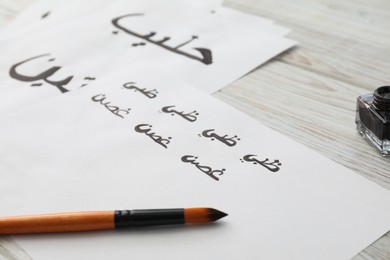 Calligraphy. Papers with word Branch in Arabian language and brush on white table, closeup