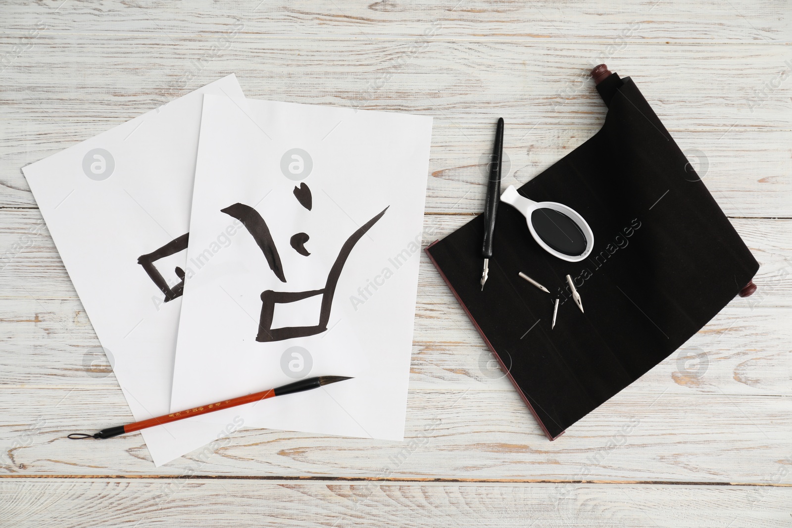 Photo of Calligraphy. Papers with written word Finish in Chinese, inkwell, fountain pen and brush on white wooden table, flat lay