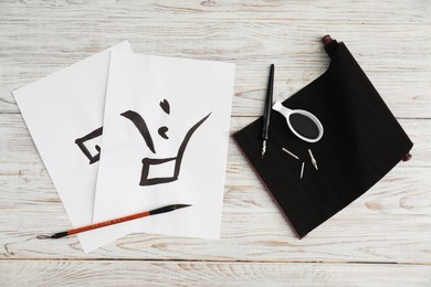 Calligraphy. Papers with written word Finish in Chinese, inkwell, fountain pen and brush on white wooden table, flat lay