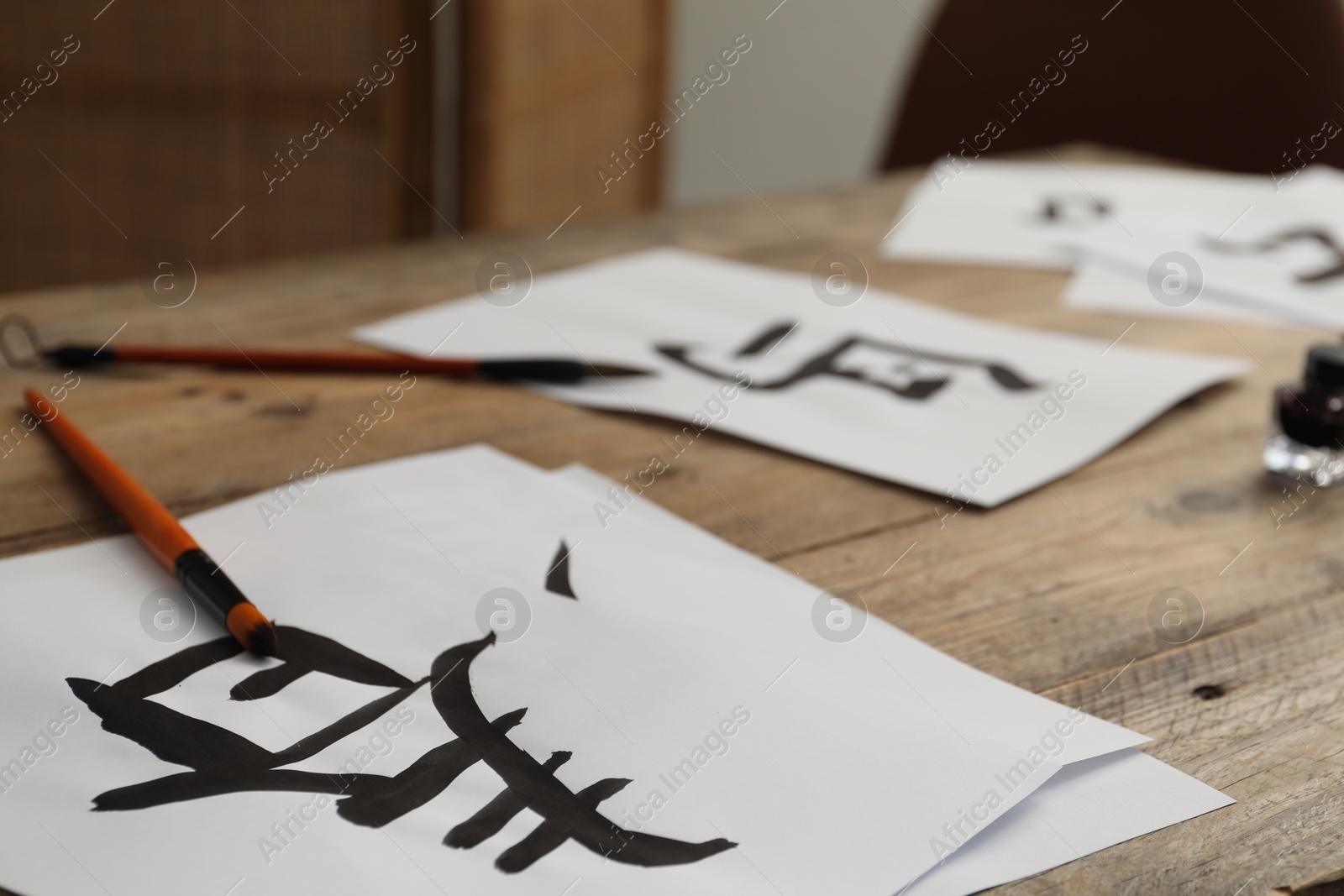 Photo of Calligraphy. Paper with written word Spring in Chinese and brushes on wooden table