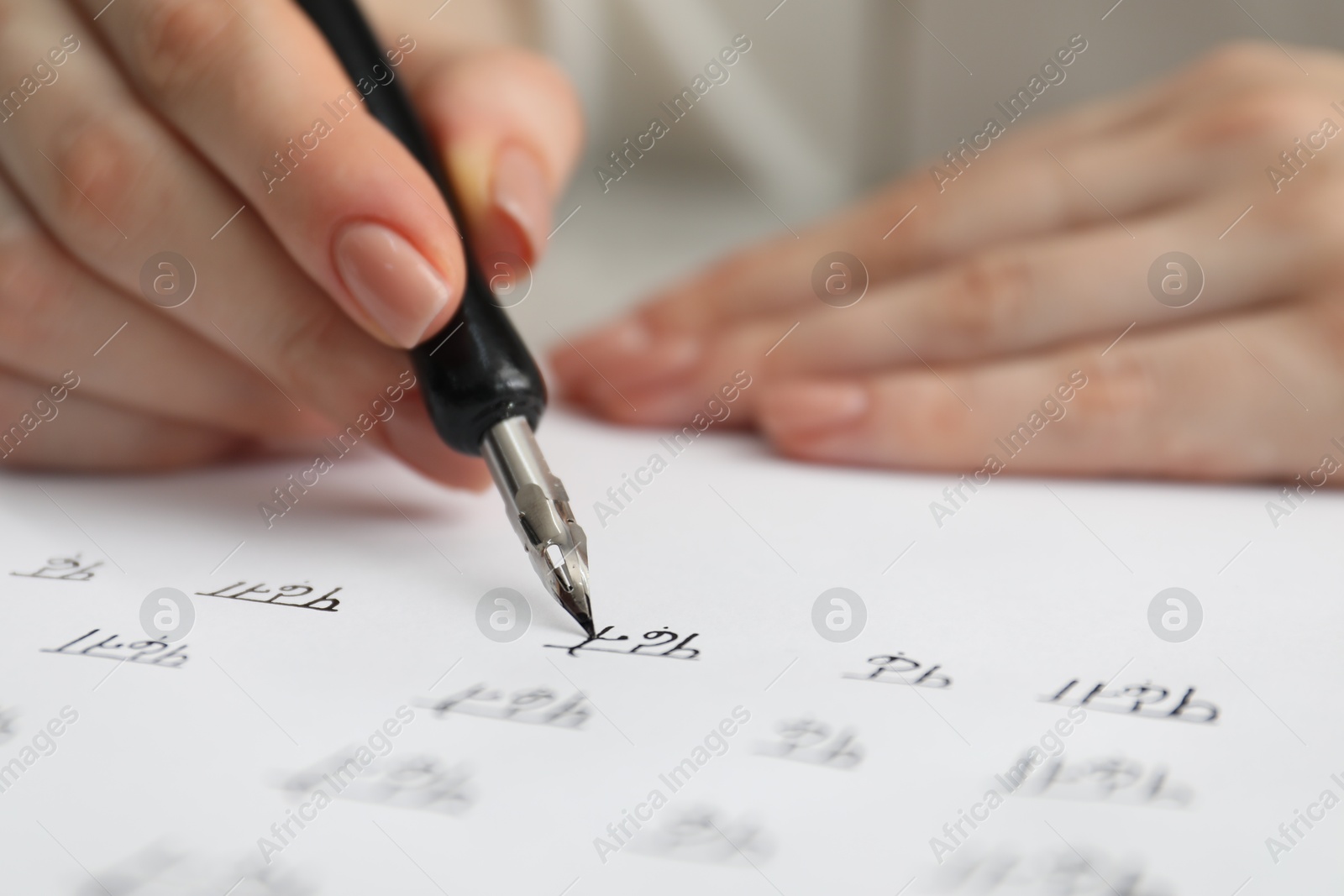 Photo of Calligraphy. Woman with fountain pen writing words Reading and Read in Hindi on paper, closeup