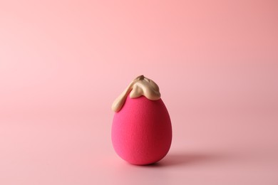 Photo of Makeup sponge with skin foundation on pink background